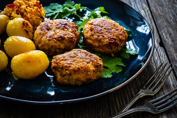 Fried pork meatballs with fried potatoes and cabbage on wooden table
