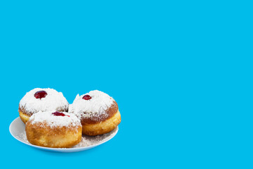 Jewish holiday Hanukkah concept. Plate with donut sufganiyot with sugar powder and jam on a blue background.