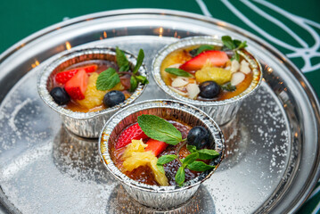 Creme brulee decorated with fresh strawberries, blueberries and mint leaves
