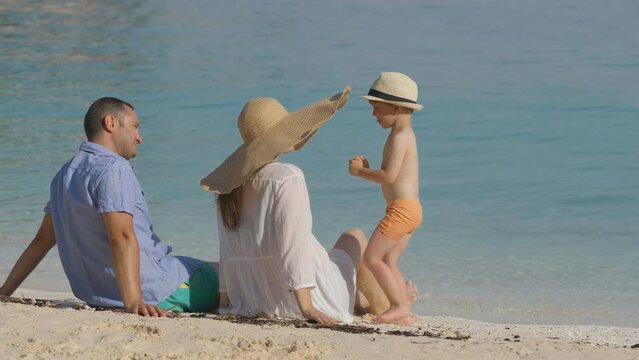 Lovely child kissing mother, family relax on beach