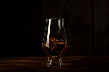 glass of whiskey with ice on a wooden background