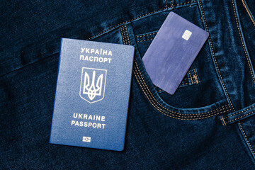 Bank card and foreign passport of a citizen of Ukraine on a denim background. Concept of refugees...