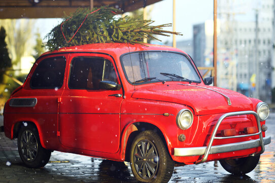 retro car with a Christmas tree on the roof against the background of falling snow.