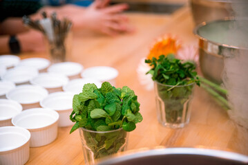 A group of empty ramekins prepared for dessert, a glass with fresh mint and nitrogen cloud