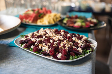 beetroot, raspberry, arugula and feta cheese salad, served on a white plate. A healthy vegetarian dish. A healthy kitchen full of vitamins and nutrients. superfoods. blurred background.