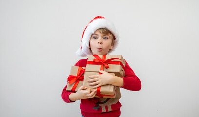 Excited funny Brazilian caucasian child girl boy wear red Santa hat holding Christmas gift boxes dreaming over white background. Copy space. Merry Christmas presents shopping sale.