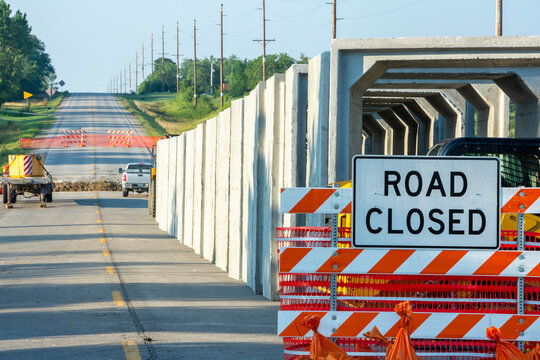 Rectangular culvert sections staged along a road closed highway sign and barricade in preparation for installation in a trench near Chariton, Iowa, USA
