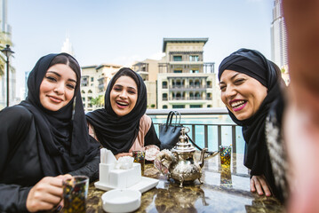 Arabic women wearing traditional middle eastern abaya clothing in Dubai, shopping and having fun outdoors