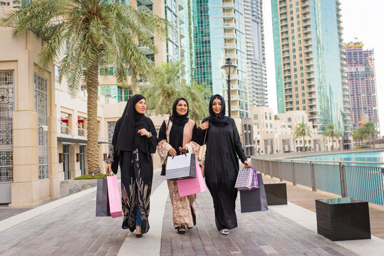 Arabic women wearing traditional middle eastern abaya clothing in Dubai, shopping and having fun outdoors