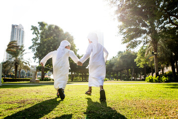Cute middle eastern kids wearing traditional arab clothing playing and having fun in a park outdoors
