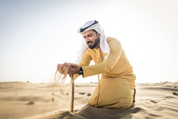 Handsome arab man wearing traditional middle eastern clothing in the desert