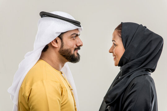 Arabian couple isolated on grey background - Arab man wearing emirates kandora and beautiful muslim woman wearing hijab 