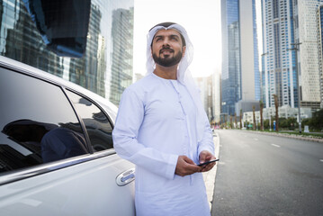 Handsome arab businessman wearing traditional emirate middle eastern clothing portrait with his luxury stretch car