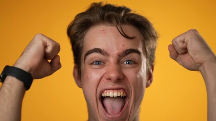 Closeup excited jubilant overjoyed young man 20s doing winner gesture celebrate clenching fists say yes isolated on yellow background studio portrait