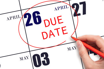 Hand writing text DUE DATE on calendar date April 26 and circling it. Payment due date