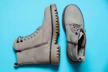 Gray women's winter boots with laces on a blue background. Concept of modern female fashion