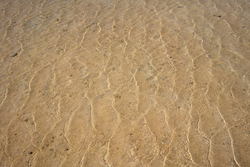 sandy bottom of the red sea at low tide with ripples from the waves