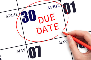 Hand writing text DUE DATE on calendar date April 30 and circling it. Payment due date