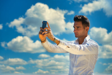 Handsome young man outside taking photo with cell phone