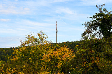 Autumnal view of the Stuttgart TV tower under a partly cloudy sky. The TV tower is surrounded by...