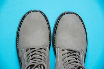 Gray women's winter boots with laces on a blue background. Concept of modern female fashion