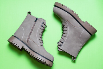 Gray women's winter boots with laces on a green background. Concept of modern female fashion