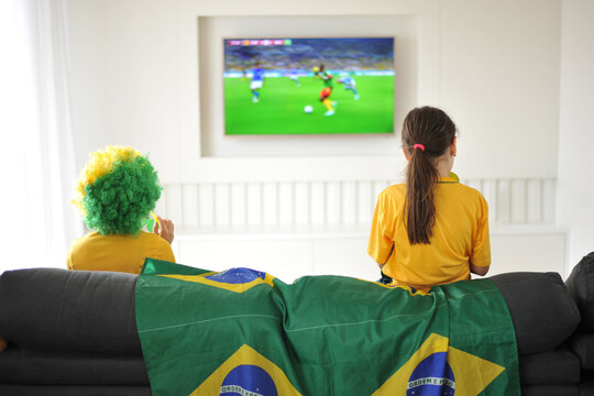 m&atilde;e e filha assistindo jogo do brasil copa do mundo pela tv em casa cores lindas 