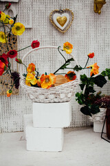 Decorated restaurant area. A decorative heart hangs on the wall of the building, next to it, on stone slabs, there is a bouquet of artificial flowers in a basket.