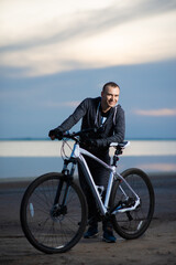 Fototapeta premium A man with a bicycle on the beach, during sunset