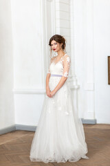 Fototapeta premium Woman bride in a wedding dress with a beautiful hairstyle, stands