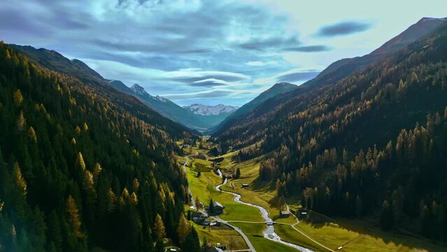 Flight over Davos mountain in autumn with beautiful colored forest and wild river