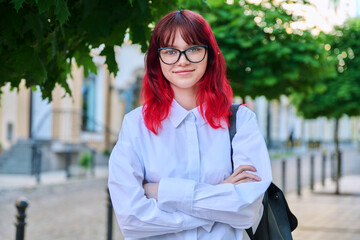 Portrait of smiling female student 18, 19 years old on city street