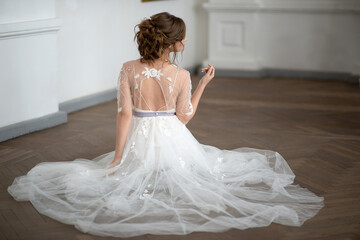 Fototapeta na wymiar female bride in wedding dress with a beautiful hairstyle sits on the floor