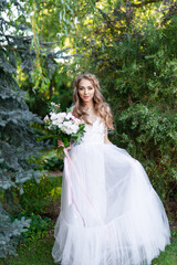 Fototapeta na wymiar bride in a white wedding dress holds a beautiful wedding bouquet in her hand in the garden
