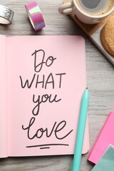 Open notebook with motivational phrase Do What You Love on wooden table, flat lay