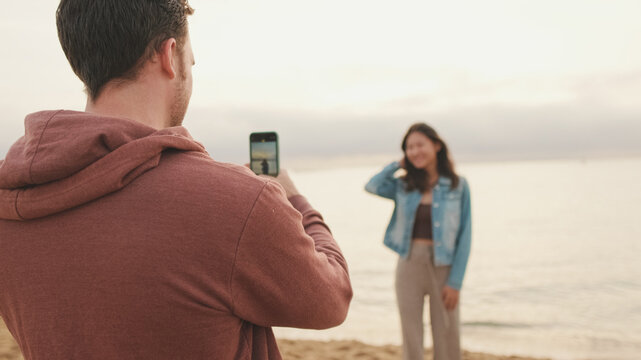 Man takes photo of woman on the shore