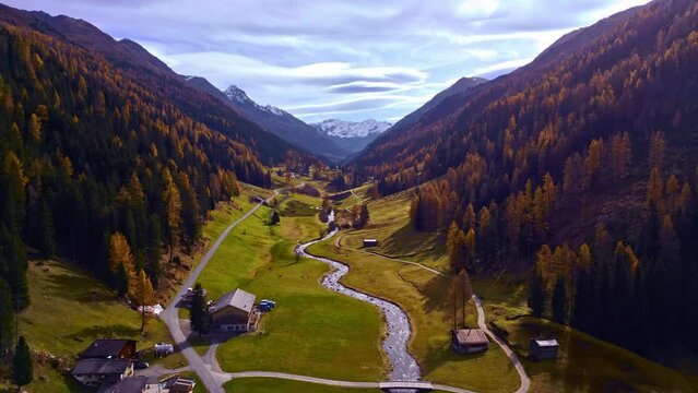Flight over Davos mountain in autumn with beautiful colored forest and wild river