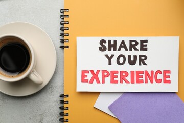 Share Your Experience. Notebook with paper notes and coffee on light grey table, flat lay