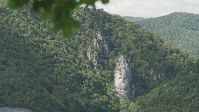 Decebalus Rex (last king of Dacia) portrait rock sculpture on Danube river bank between the green Carpathian mountains in Romania, Europe