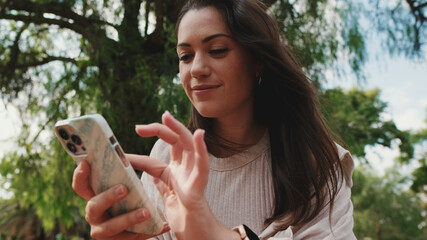 Close up, young woman using phone in the park