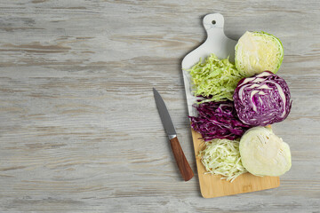Different types of cut cabbage and knife on white wooden table, flat lay. Space for text