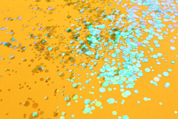 Shiny bright glitter scattered on orange background
