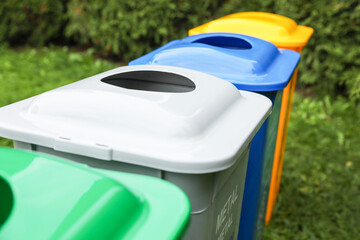 Fototapeta na wymiar Many color recycling bins on green grass outdoors, closeup