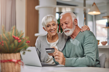an embracing elderly couple shopping online for Christmas
