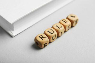 Word Rules made of wooden cubes with letters and book on white table