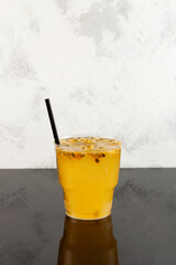 Iced Yuzu drink with Passion fruit and Orange juice in disposable plastic cup. Take away food and drink. Refreshing fruit cocktail, side view