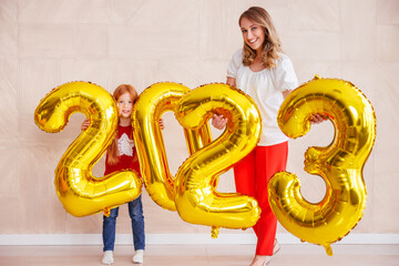 Mother and daughter holding balloons 2023 while celebrating New Year