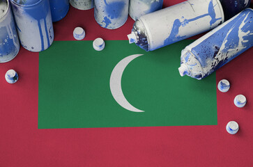 Maldives flag and few used aerosol spray cans for graffiti painting. Street art culture concept,...