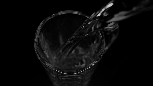 Pour water into glasses separately on black background.
