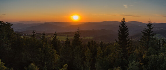 sunset in the forest with low mountains in the background